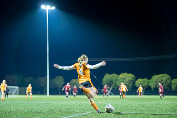 Girl playing soccer under lights at night time